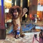 A Royal Caribbean lion mascot is taking a picture of a child aboard the Allure of the Seas cruise ship.