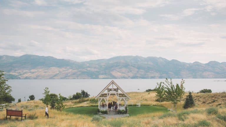 A destination wedding in front of a picturesque lake with majestic mountains in the background.