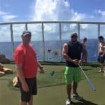 Two men posing on a golf course on the Royal Caribbean Allure of the Seas cruise ship.