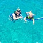 A woman and child diving in the clear blue water on Royal Caribbean's Allure of the Seas.
