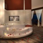 A Secrets Maroma Beach bathroom featuring a large tub and red rose petals.