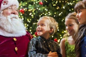 Children in front of a Christmas tree with Santa Claus.
