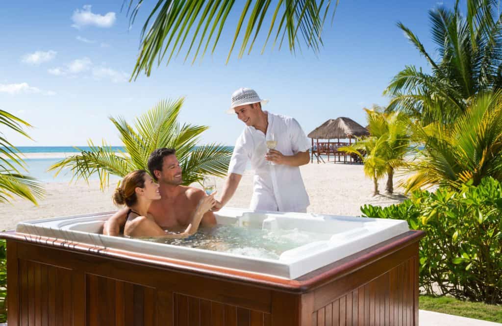Two people enjoying a romantic Valentines Day getaway while relaxing in a hot tub on the beach.