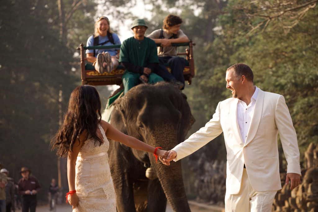 A couple enjoys a romantic stroll on an elephant during their exotic destination wedding.