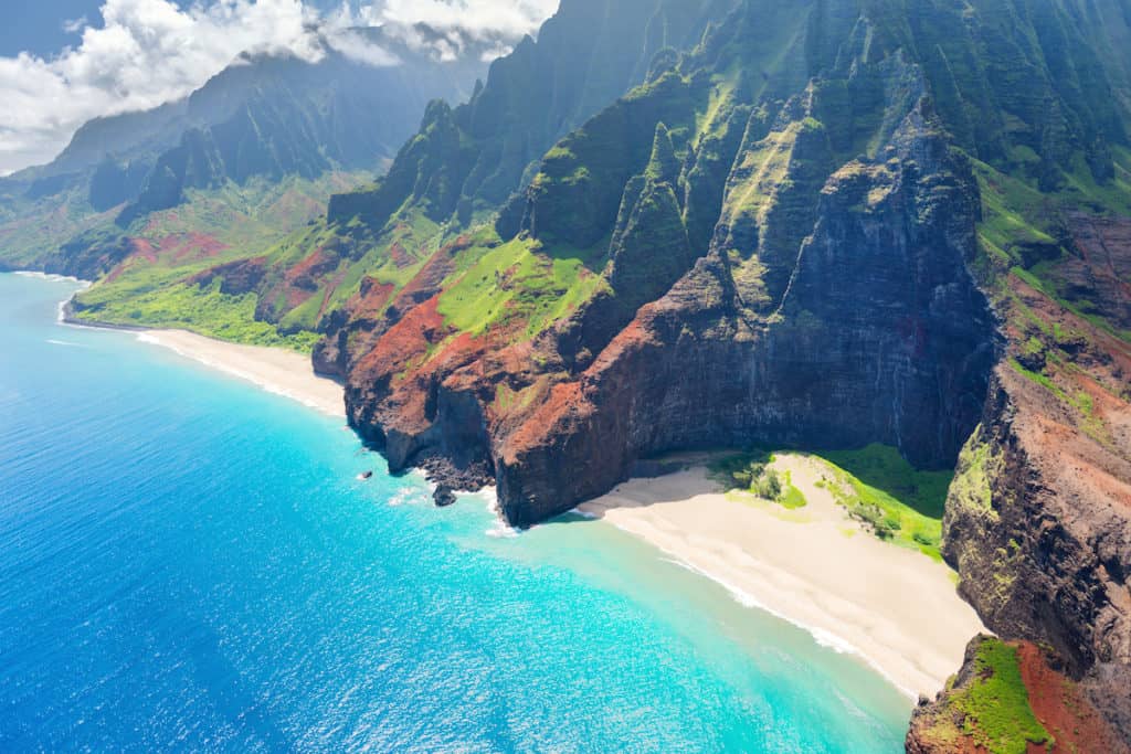 Aerial view of the best Hawaiian island, showcasing a stunning beach and majestic cliffs.