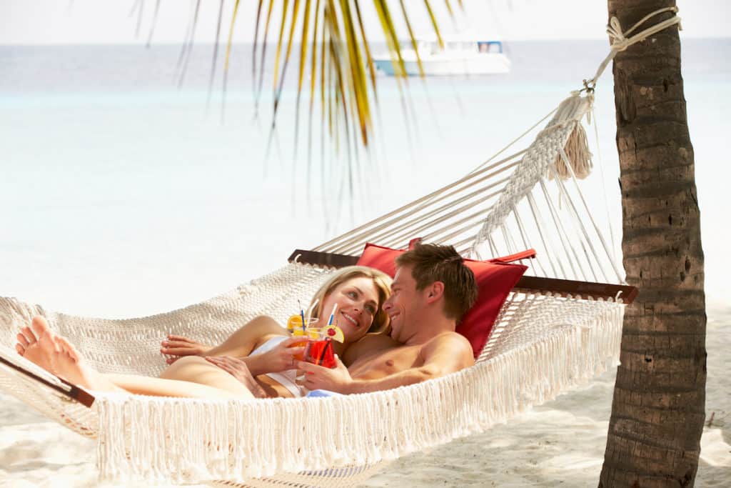 A couple enjoying a hammock on the beach during an adult-only vacation.