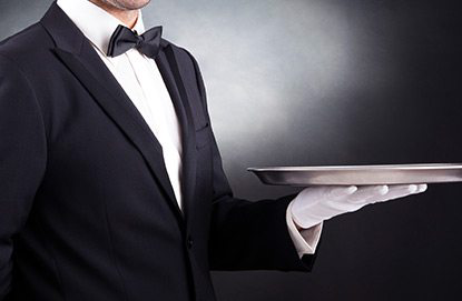 A waiter in a tuxedo holding a tray at Fox Travel