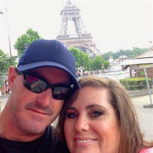 A man and woman meet in front of the Eiffel Tower and take a selfie together.