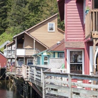 A row of colorful houses on a dock near a body of water, showcasing the vibrant charm of an Alaska Cruise.