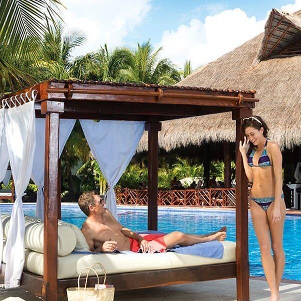A man and a woman enjoying El Dorado Resorts sitting on a bed next to a pool.